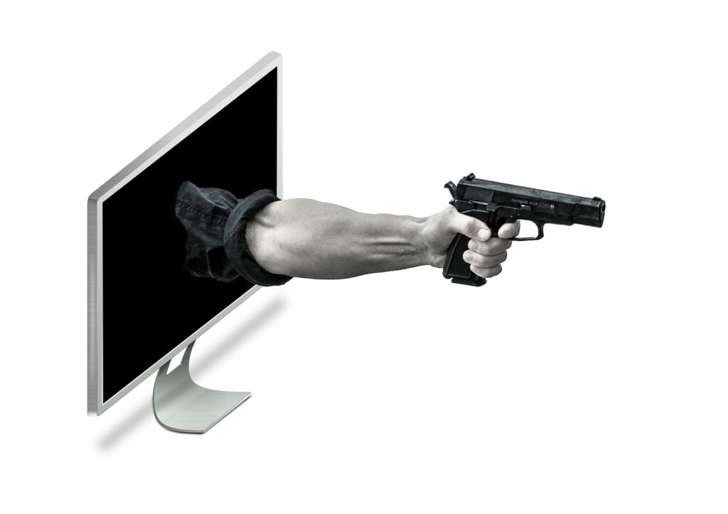 workplace violence insider threat with arm holding a pistol extended from a computer screen